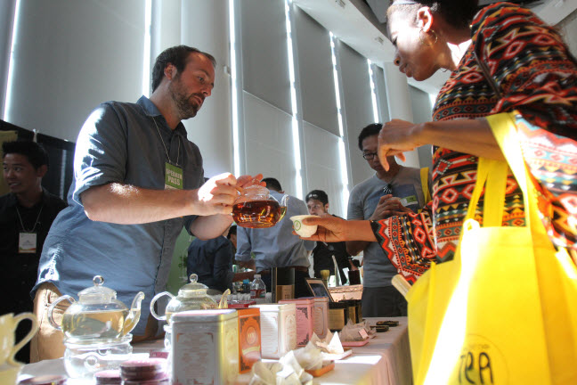 Alexander Harney of the Marketing Department, Harney and Sons, pours a sample for an attendee. 